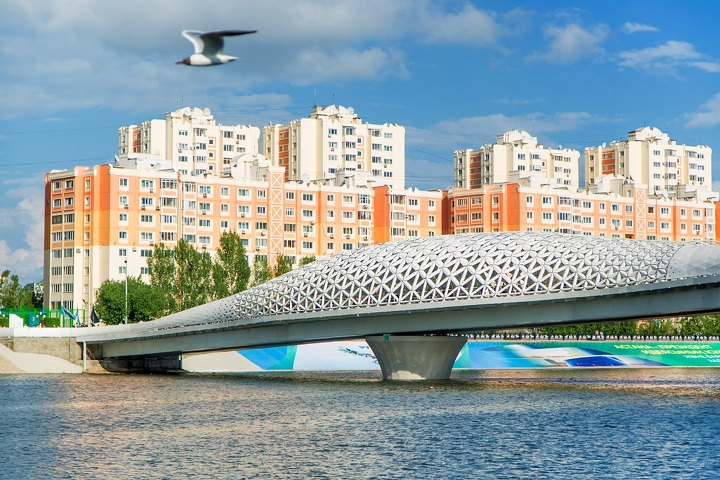 Атырауский пешеходный мост через Ишим — белый ажурный купол на фоне жилых домов правого берега